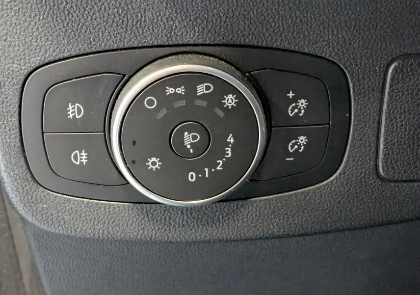Gros plan sur la molette de réglage des phares et des feux antibrouillard dans l’habitacle d’une Ford Puma gris 2020.