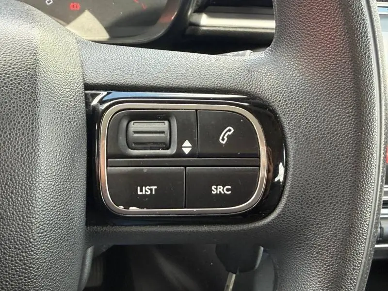 Gros plan sur les commandes audio au volant de la Citroën C3 PureTech 82ch Feel, finition noire texturée.