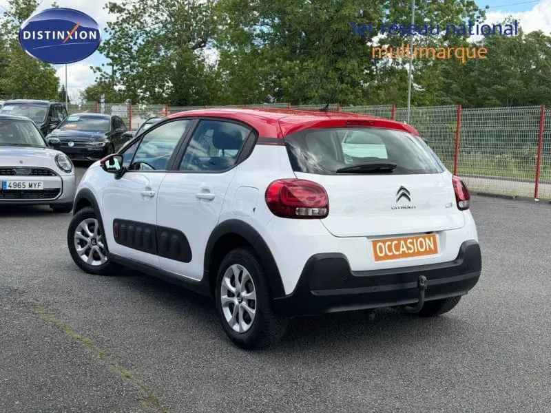 Citroën C3 PureTech 82ch Feel 2017 vue 3/4 arrière, blanc banquise avec toit rouge Aden et Airbump noir sur porte.