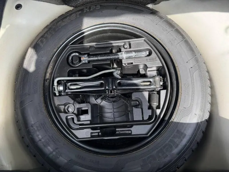 Vue en plongée du pneu de secours noir et de ses outils de bord dans le coffre d'une Citroën C3 PureTech 82ch Feel 2017.