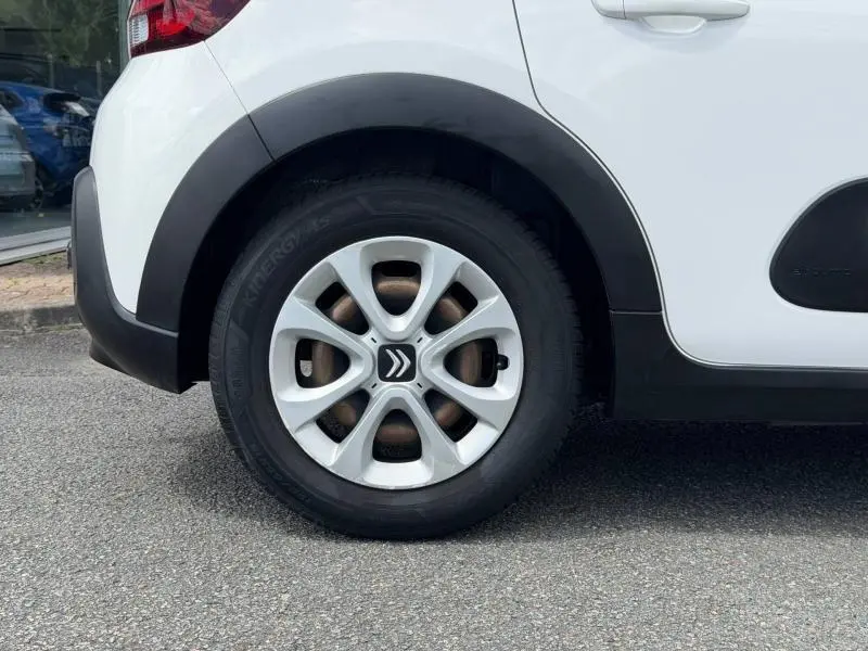 Gros plan sur la roue arrière droite d'une Citroën C3 blanche Banquise avec jante en alliage et élargisseur d'aile noir.