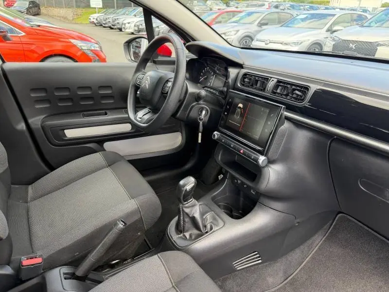 Vue intérieure côté conducteur de la Citroën C3 PureTech 82ch Feel 2017 avec tableau de bord noir et sièges tissu gris.