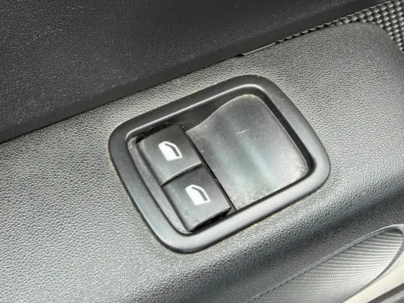 Gros plan sur les commandes des vitres électriques côté conducteur d'une Citroën C3 2017 blanc banquise et rouge aden.