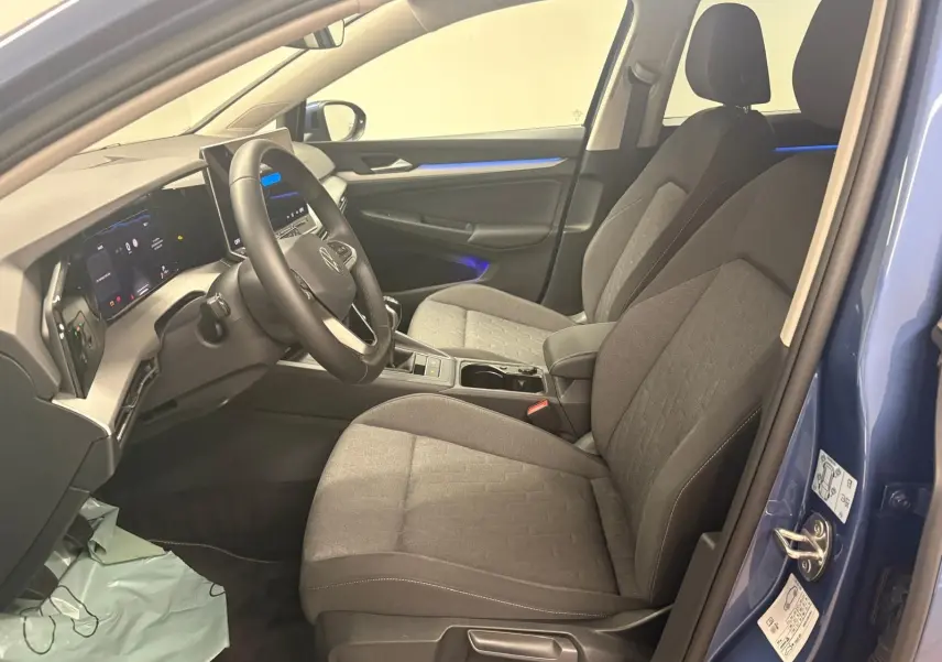 Vue intérieure côté conducteur de la Volkswagen Golf 1.5 TSI 116 BVM6 Bleu Anémone avec sièges tissu gris et éclairage d'ambiance bleu.