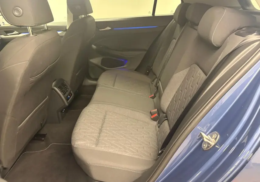 Vue intérieure côté droit des sièges arrière gris et de la portière bleu anémone d'une Volkswagen Golf 1.5 TSI 2025.