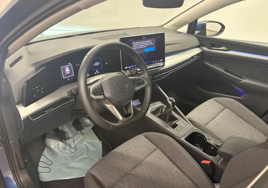 Vue intérieure côté conducteur de la Volkswagen Golf 1.5 TSI 116 BVM6 VW Edition avec tableau de bord numérique et sellerie grise.