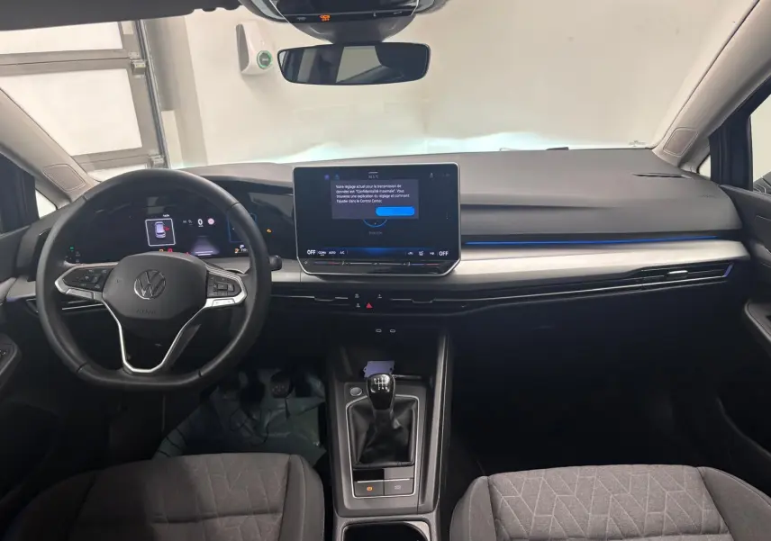Vue intérieure avant du tableau de bord de la Volkswagen Golf Bleu Anémone avec écran tactile et volant multifonction.