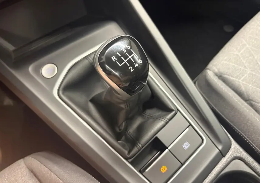 Gros plan sur le levier de vitesse manuel noir et cuir de la Volkswagen Golf, entouré de la console centrale grise.
