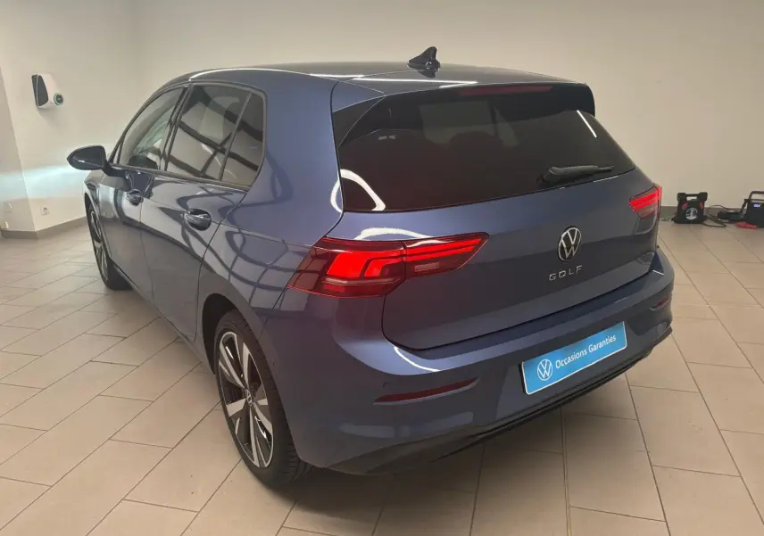 Vue 3/4 arrière droite d'une Volkswagen Golf 1.5 TSI 2025 en bleu anémone avec jantes alliage 18'' Catania.