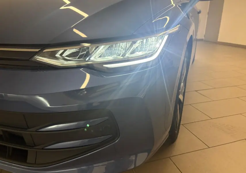 Gros plan sur l'avant droit de la Volkswagen Golf Bleu Anémone avec phare allumé et jante alliage 18 pouces.