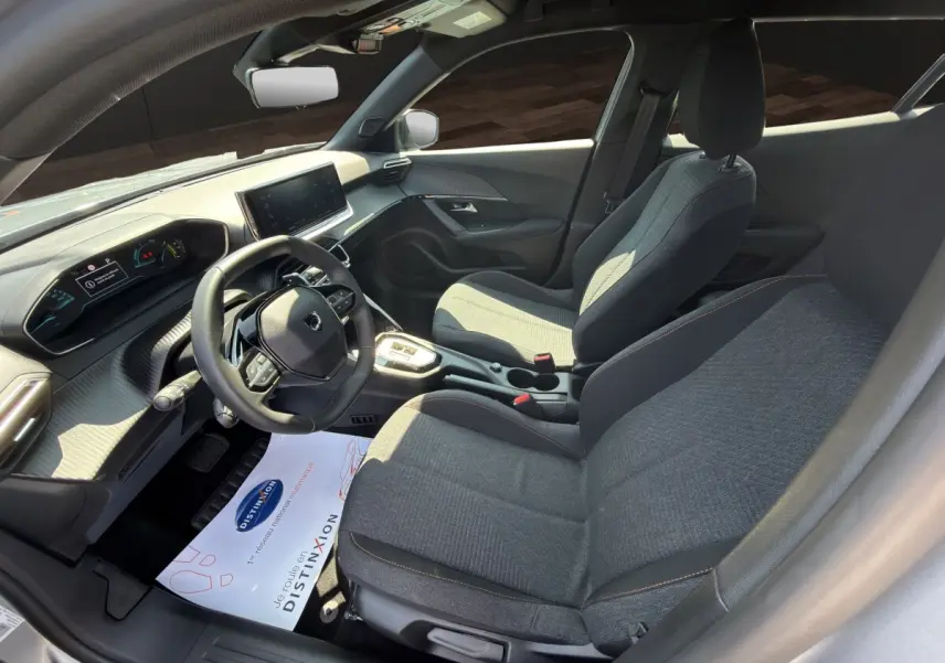 Vue intérieure côté conducteur du Peugeot 2008 Hybrid 145 e-DCS6 STYLE 2025 avec sièges gris et tableau de bord moderne.