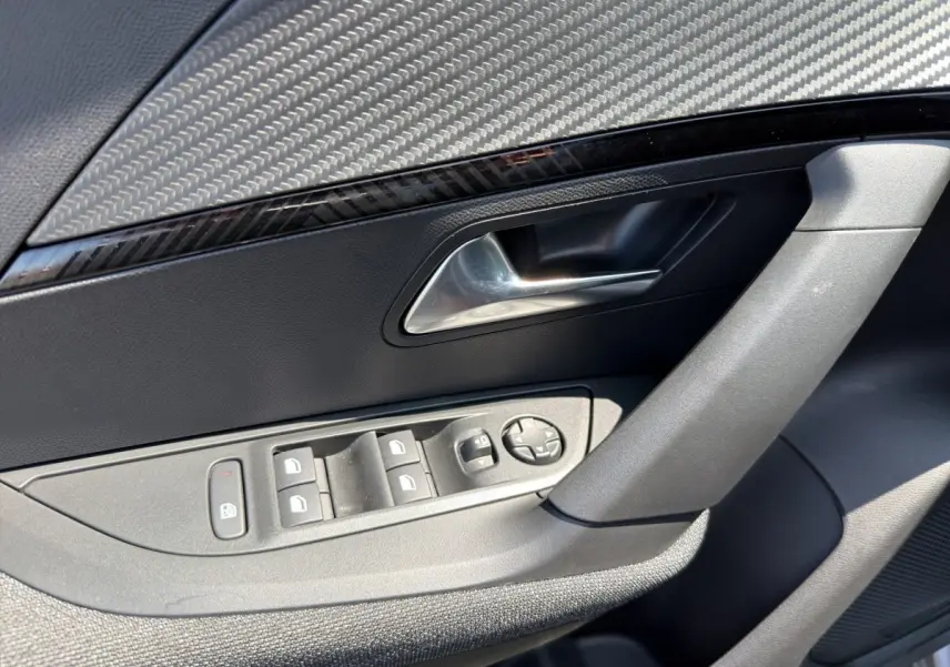 Détail de la porte côté conducteur du Peugeot 2008 gris clair, avec commandes électriques et poignée argentée.