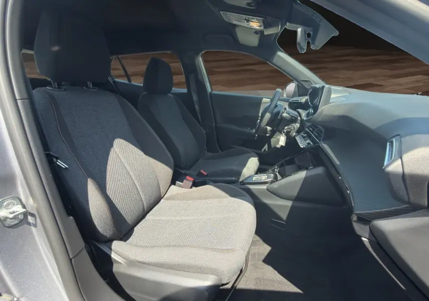 Vue intérieure côté conducteur du Peugeot 2008 Hybrid 145 gris clair, montrant sièges tissu et tableau de bord moderne.