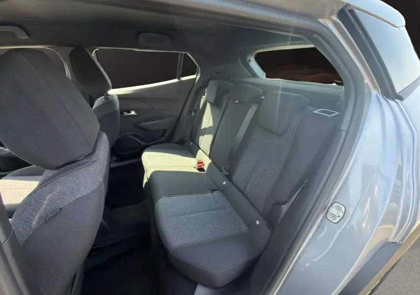 Vue intérieure côté arrière droit de la Peugeot 2008 Hybrid 145 gris clair, montrant la banquette et les sièges tissu.