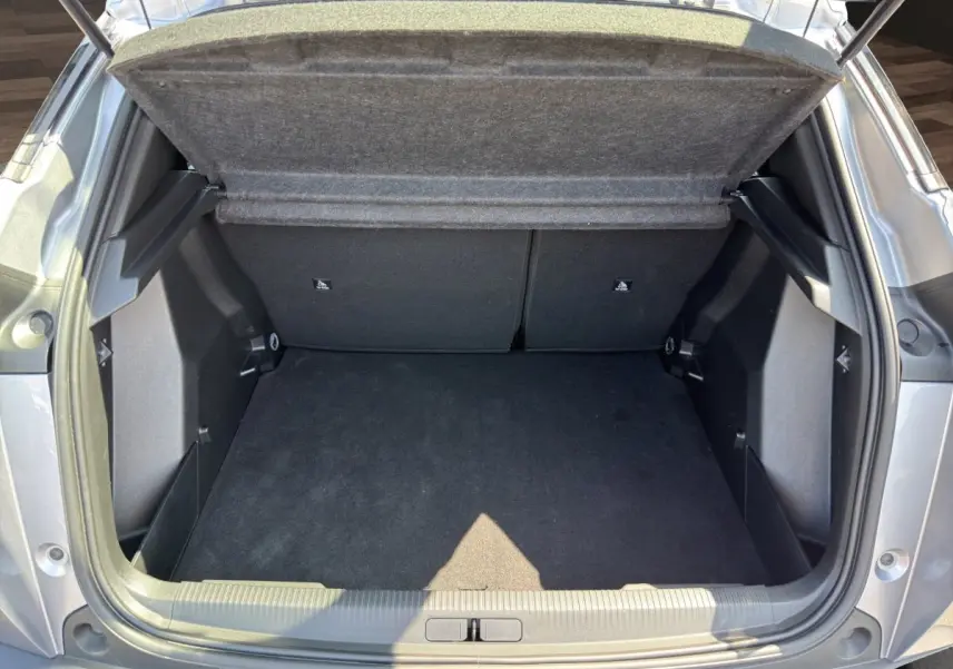 Coffre ouvert vu de l'arrière d'un Peugeot 2008 Hybrid 145 gris clair, espace de chargement propre et vide.