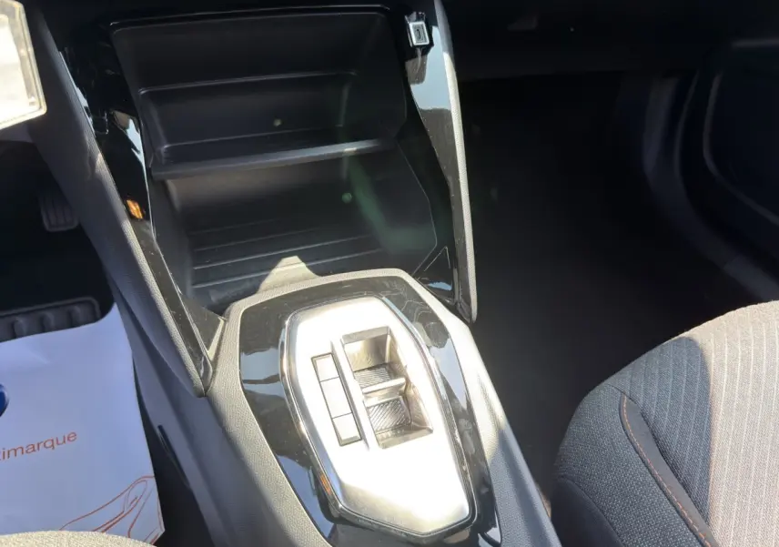 Vue intérieure centrée sur la console centrale noire brillante et la commande de boîte automatique du Peugeot 2008 gris clair.