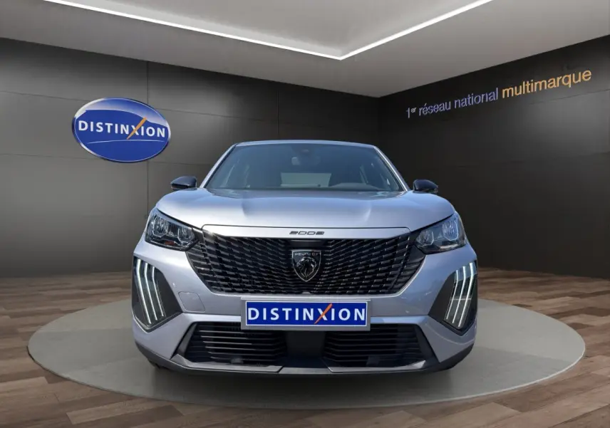Vue frontale d'un Peugeot 2008 Hybrid 145 gris clair avec calandre noire et feux LED verticaux distinctifs.