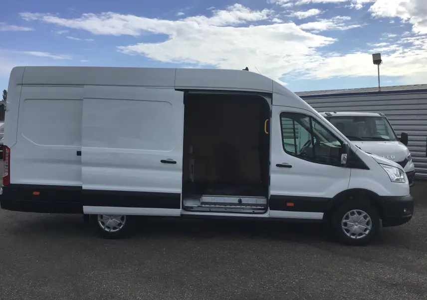 Vue de profil côté gauche d'un fourgon Ford Transit blanc 2020 avec porte latérale coulissante ouverte montrant l'intérieur vide.