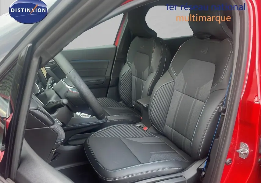 Vue intérieure côté conducteur du Renault Captur E-Tech hybride rouge passion, mettant en valeur les sièges en cuir noir avec surpiqûres bleues.