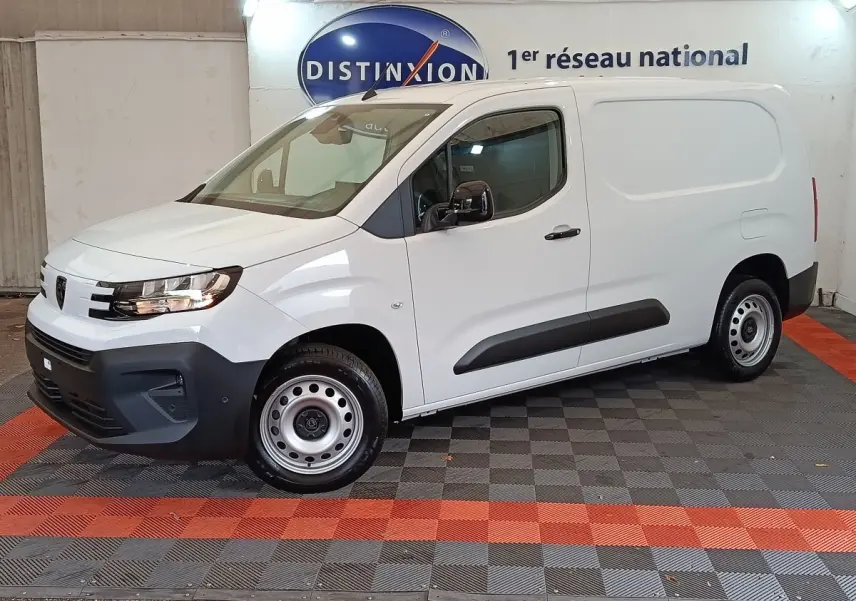 Vue de profil côté gauche d'un utilitaire Peugeot Partner XL blanc avec protections latérales noires en intérieur showroom.