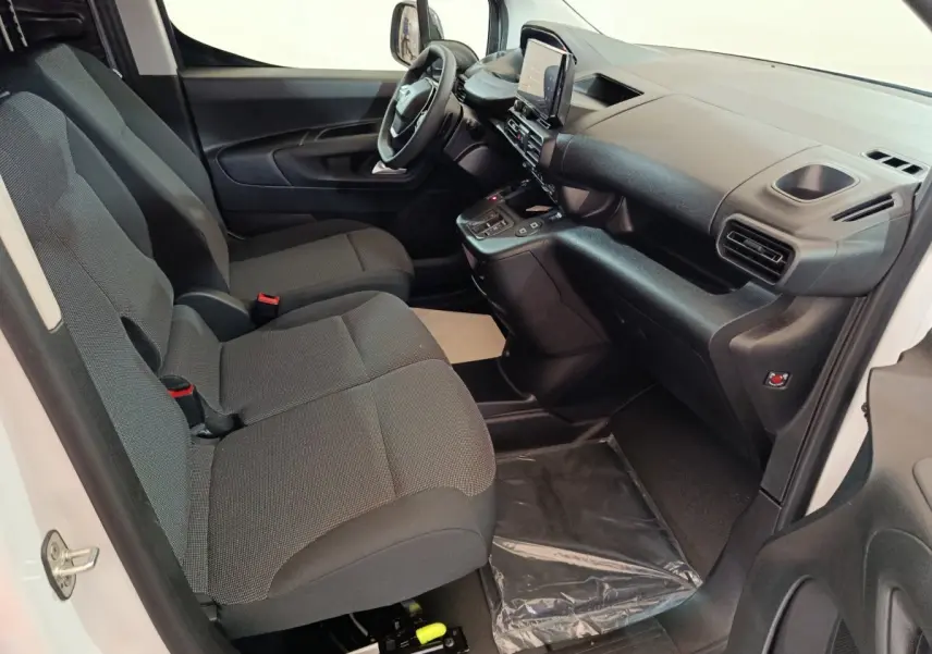 Intérieur avant du Peugeot Partner XL 2025 blanc, montrant sièges gris et tableau de bord moderne avec écran tactile central.