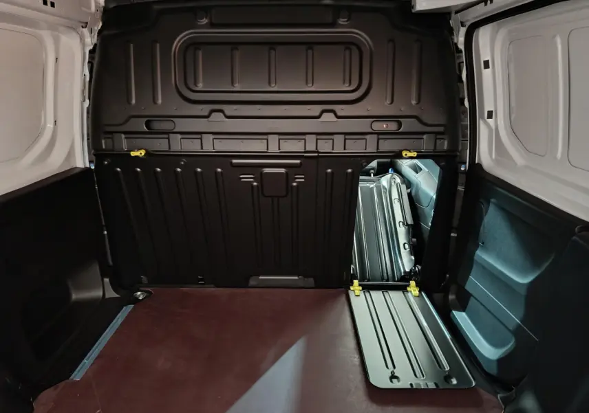 Vue intérieure du coffre blanc du Peugeot Partner XL 950kg avec cloison pleine noire et plancher marron.