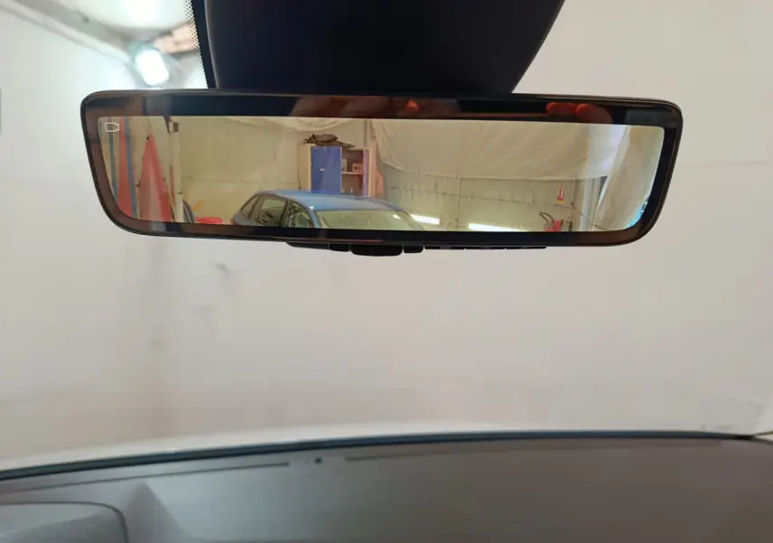 Rétroviseur intérieur affichant en reflet une voiture bleue vue de trois quarts arrière dans un garage.