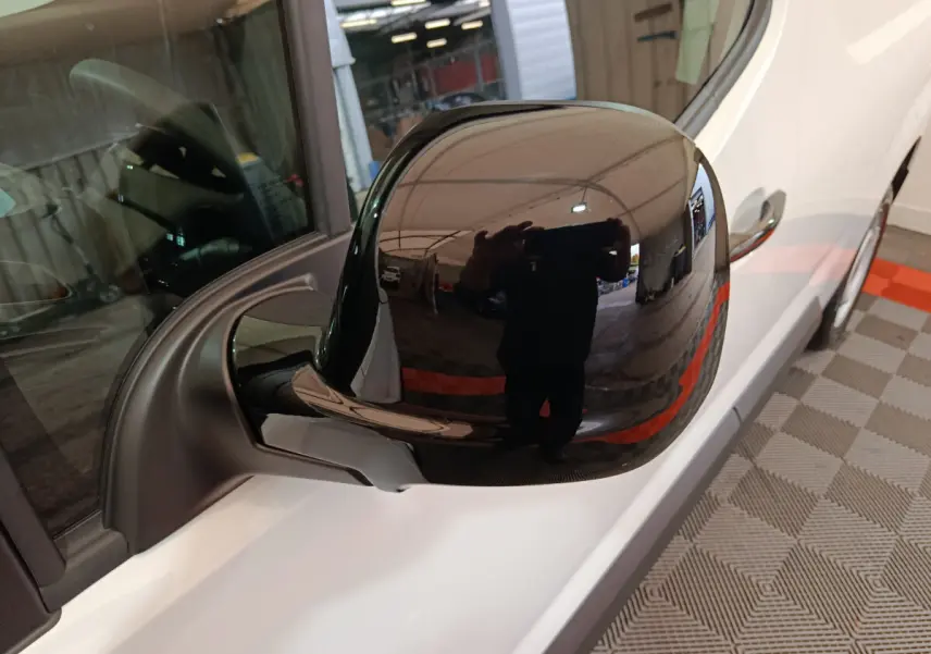 Rétroviseur noir côté conducteur du Peugeot Partner XL blanc, vue rapprochée en intérieur d'atelier.