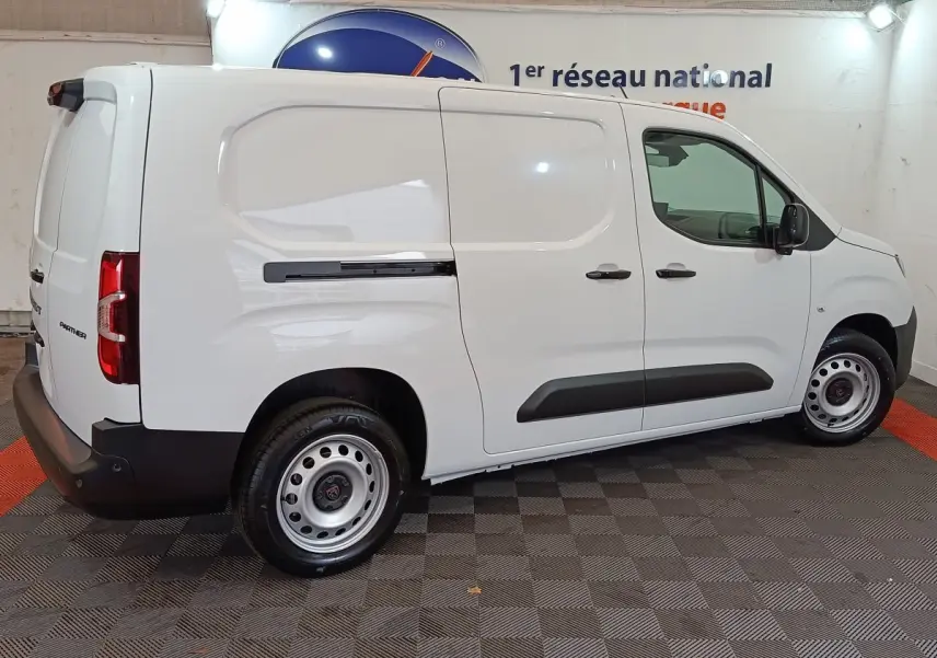 Peugeot Partner XL blanc vu de profil côté droit dans un showroom avec jantes acier et protections noires.