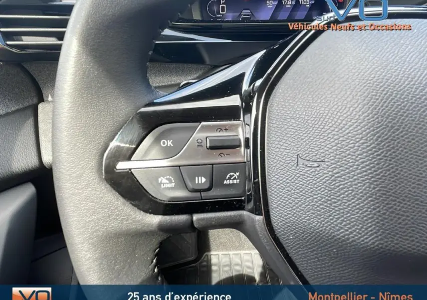 Gros plan sur le volant noir de la Peugeot 308 gris 2024, montrant les commandes de régulateur et limiteur de vitesse.