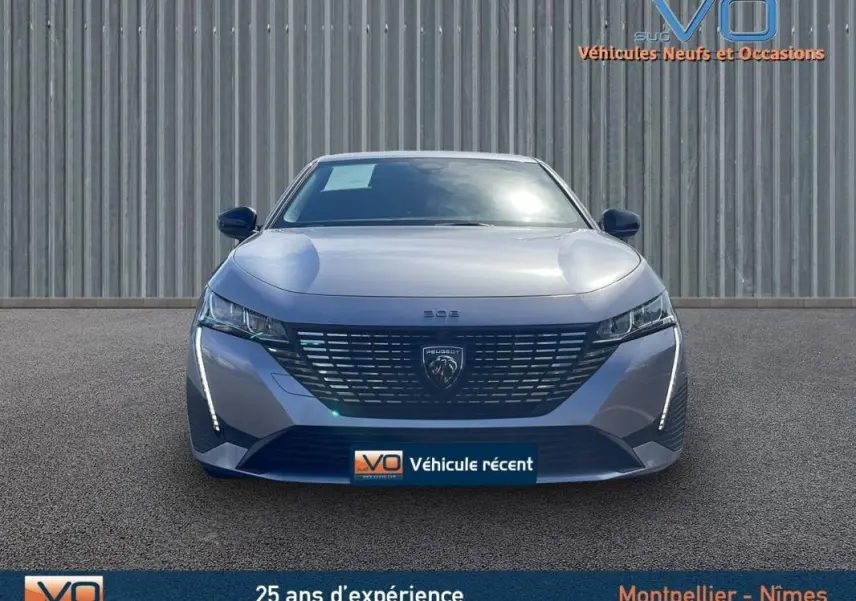 Vue frontale d’une Peugeot 308 gris métallisé 2024 avec calandre distinctive et feux LED verticaux allumés.