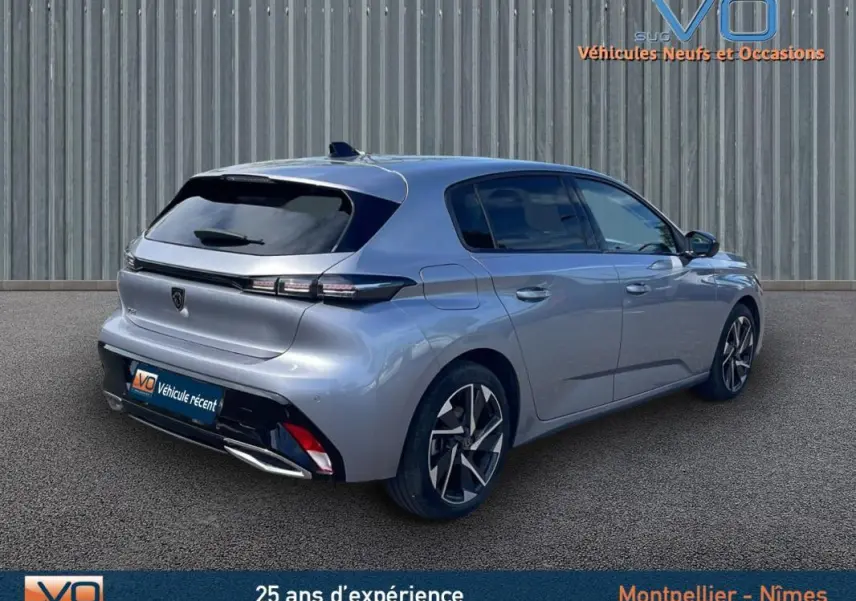 Peugeot 308 gris métallisé vue 3/4 arrière droit, avec jantes alliage et feux arrière LED distinctifs.