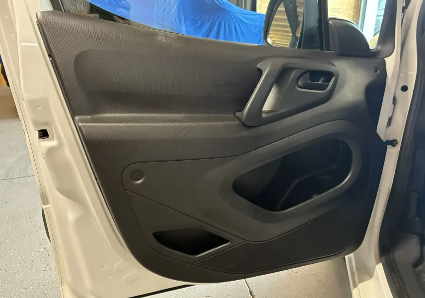 Vue intérieure de la porte avant gauche noire du Citroën Berlingo blanc 2016, avec poignée intégrée et rangement.