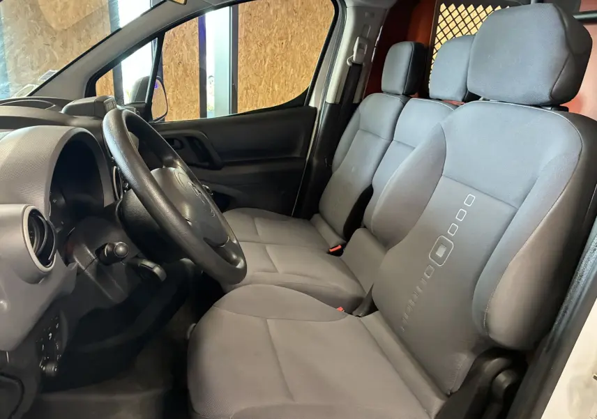 Vue intérieure côté conducteur du Citroën Berlingo 1.6 BlueHDi 100 de 2016, sièges tissu gris et tableau de bord noir.