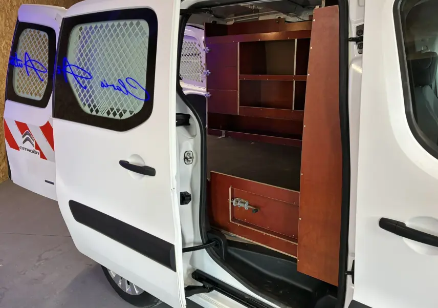 Vue côté droit en plan rapproché d’un Citroën Berlingo blanc 2016 avec portes arrière ouvertes et aménagement bois intérieur.