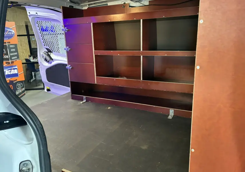 Vue intérieure arrière gauche du Citroën Berlingo blanc 2016 avec aménagements en bois pour rangement.