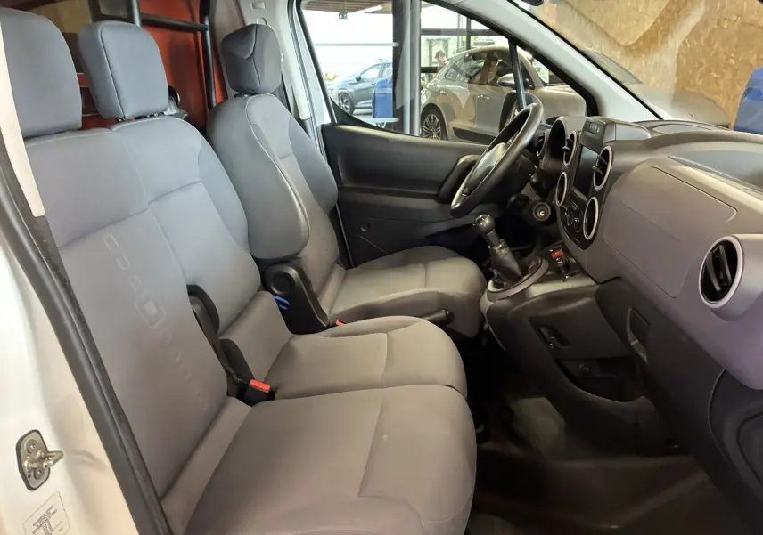 Vue intérieure côté droit du Citroën Berlingo blanc 2016, montrant les sièges avant gris et la console avec boîte manuelle.