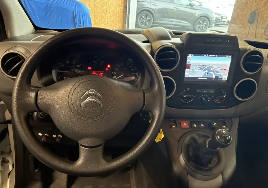 Vue intérieure du tableau de bord du Citroën Berlingo blanc 2016, volant, GPS et levier de vitesse manuel visibles.
