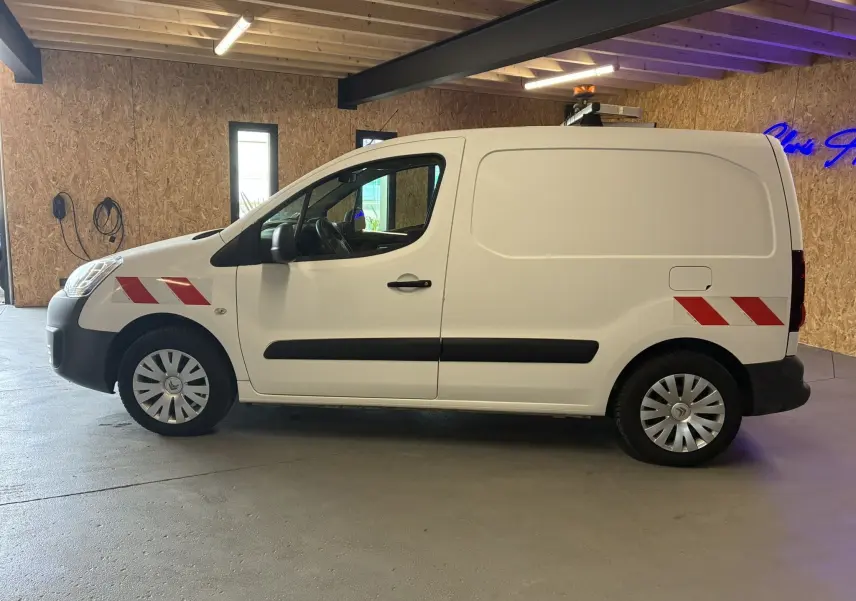 Vue de profil côté gauche d’un Citroën Berlingo blanc 2016 avec bandes réfléchissantes rouges sur les ailes avant et arrière.