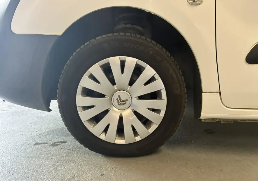 Gros plan sur la roue avant gauche blanche d’un Citroën Berlingo 1.6 BlueHDi 2016 avec enjoliveur argenté.