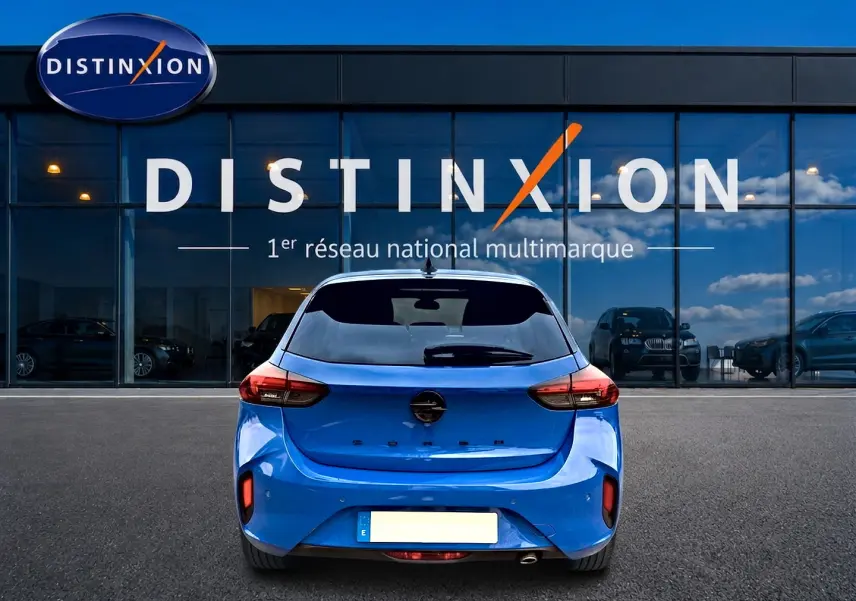 Vue arrière d'une Opel Corsa bleu vif garée devant une vitrine avec logo Distinxion.