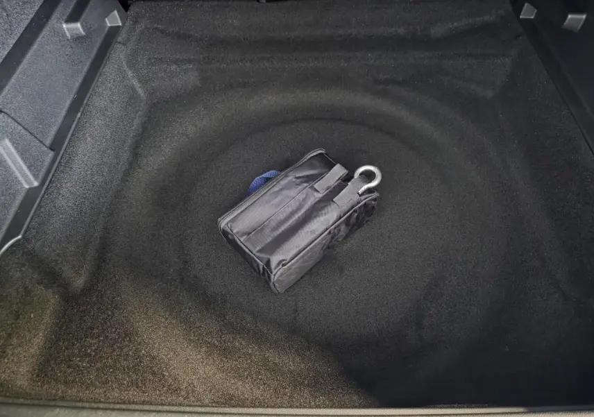 Coffre ouvert du Peugeot 3008 bleu, montrant un rangement sous plancher avec trousse de dépannage noire.