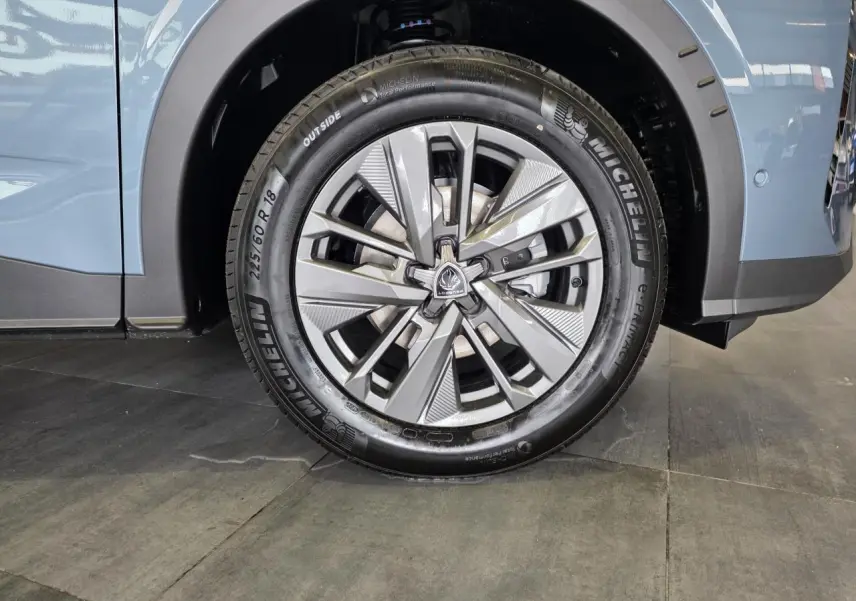 Gros plan sur la roue avant droite du Peugeot 3008 bleu, jante alliage 18 pouces au design moderne.