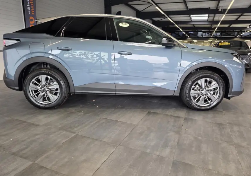 Vue de profil côté gauche d'un Peugeot 3008 hybride bleu avec jantes alliage 18 pouces en intérieur showroom.
