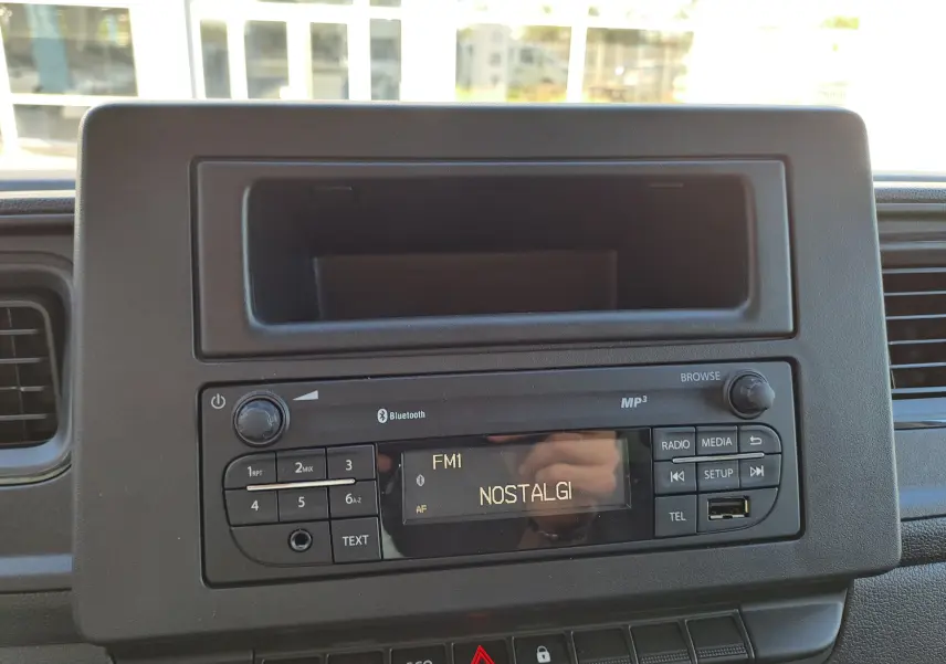 Vue rapprochée de la radio Bluetooth MP3 du tableau de bord noir du Nissan Interstar blanc, avec écran affichant la station FM1 NOSTALGI.