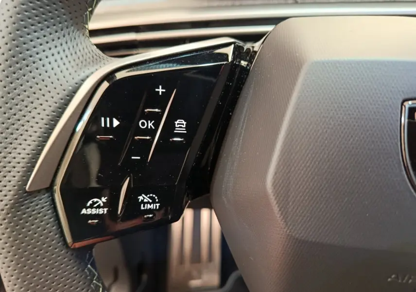 Gros plan sur les commandes noires multifonctions du volant cuir perforé du Peugeot 3008 blanc 2025 hybride.