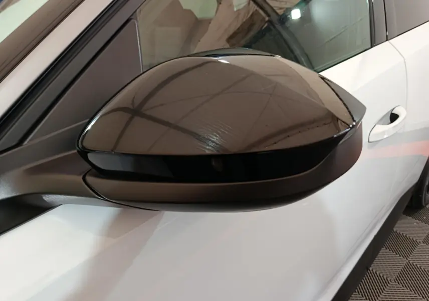 Rétroviseur noir brillant côté gauche du Peugeot 3008 blanc, avec porte et poignée visibles en arrière-plan.