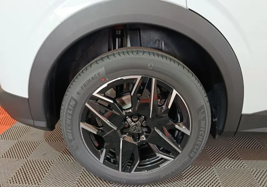Gros plan sur la roue avant droite du Peugeot 3008 blanc, mettant en valeur la jante noire brillante au design moderne.