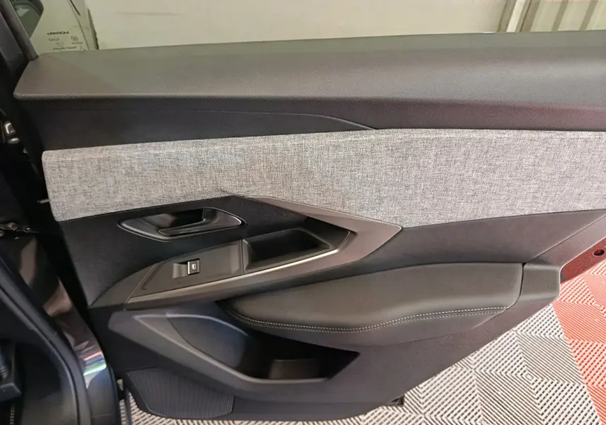 Gros plan sur la porte intérieure côté gauche du Peugeot 3008 blanc, avec garniture tissu gris et cuir noir.