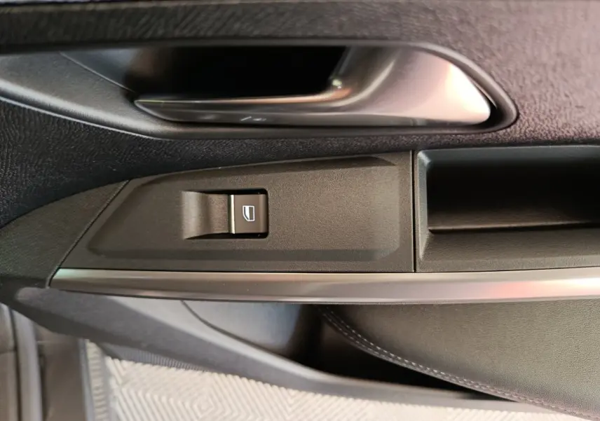 Détail de la poignée intérieure côté gauche du Peugeot 3008 blanc, avec bouton de commande de vitre et insert métal.